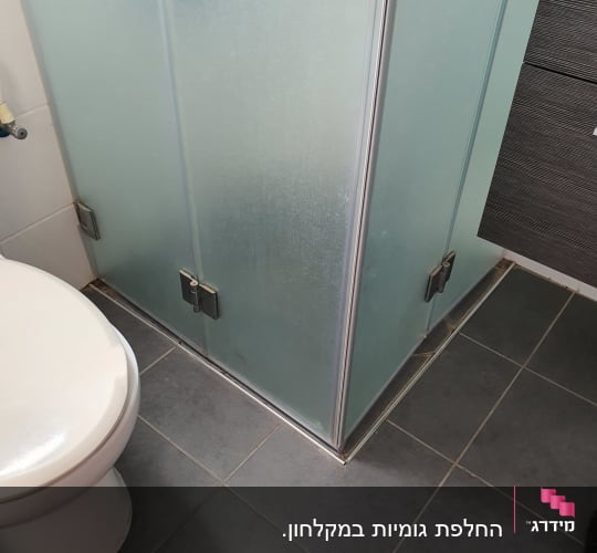 מקלחון זכוכית עם דלתות מתכת בחדר אמבטיה